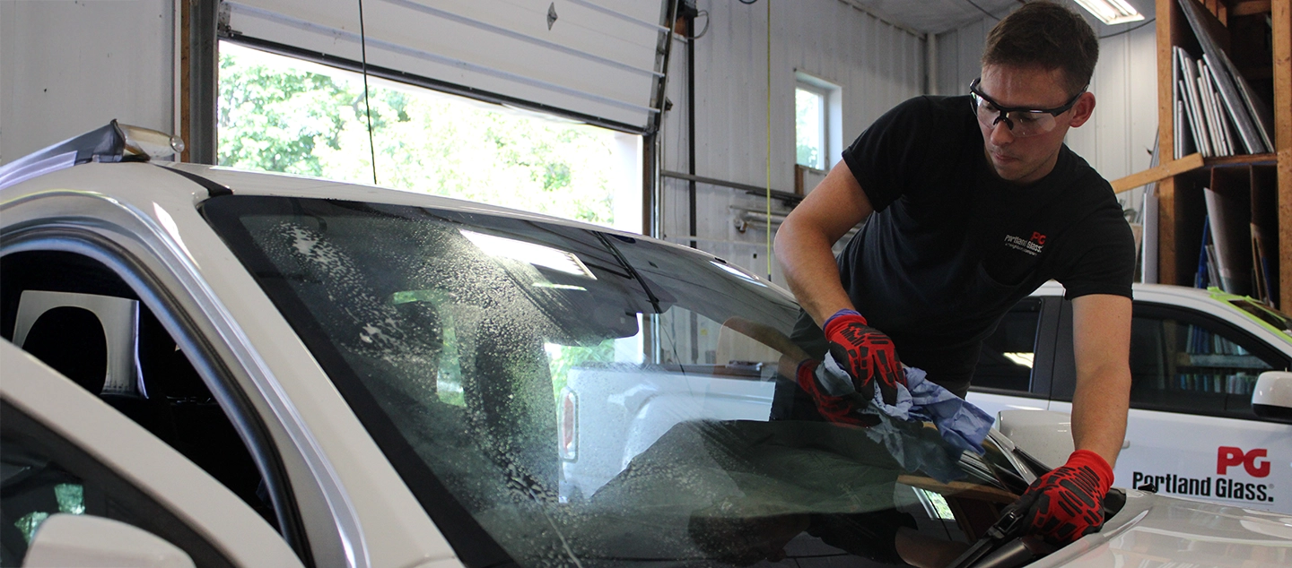 A Portland Glass technician works on a customer's car windshield.