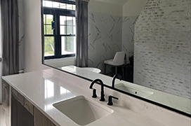 A glass mirror hanging above a bathroom vanity.