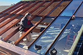 A picture of a Portland Glass technician installing a glass rooftop.