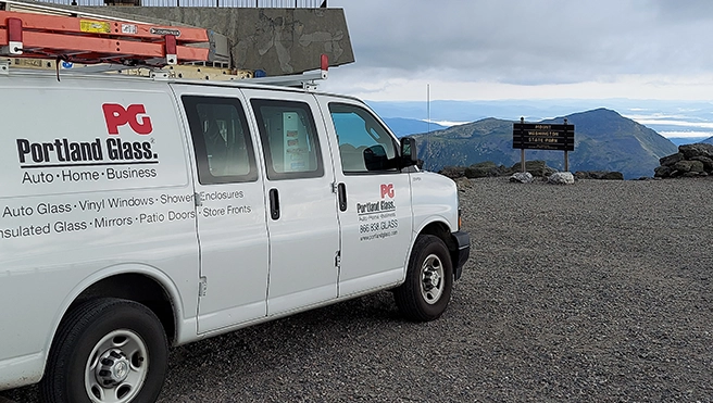 A picture of a Portland Glass van parked at a mountain overlook.
