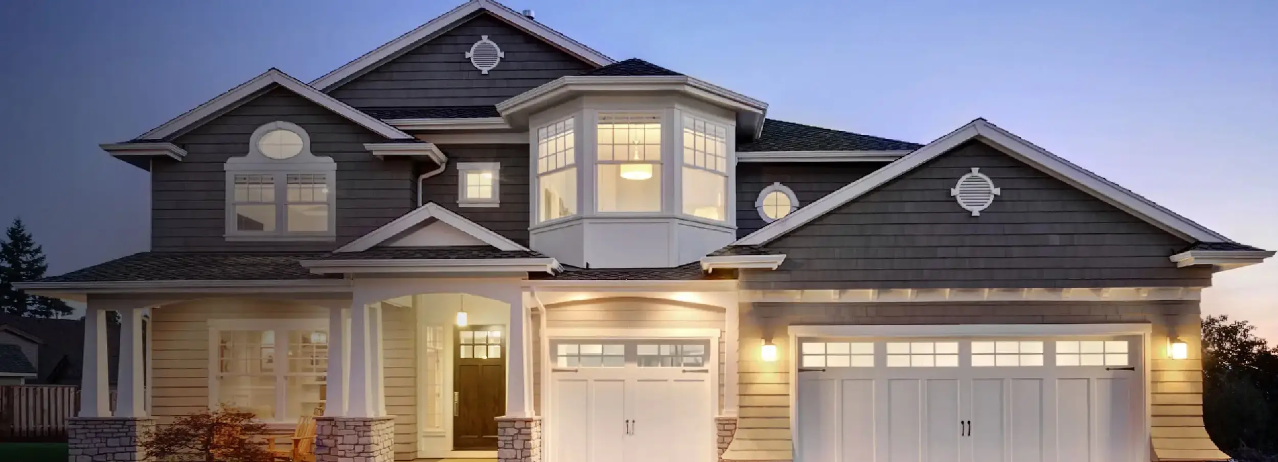 Exterior of a craftsman style home at dusk with outdoor lights on.