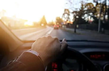 hand on steering wheel with view out of windshield.